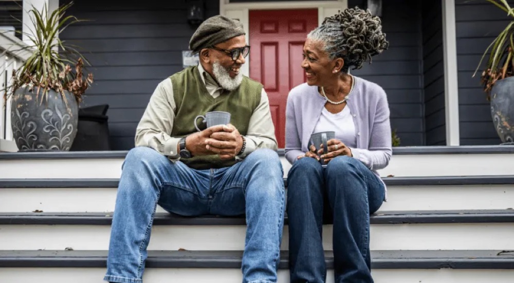 Aging couple on a stoop with coffee mugs in hand